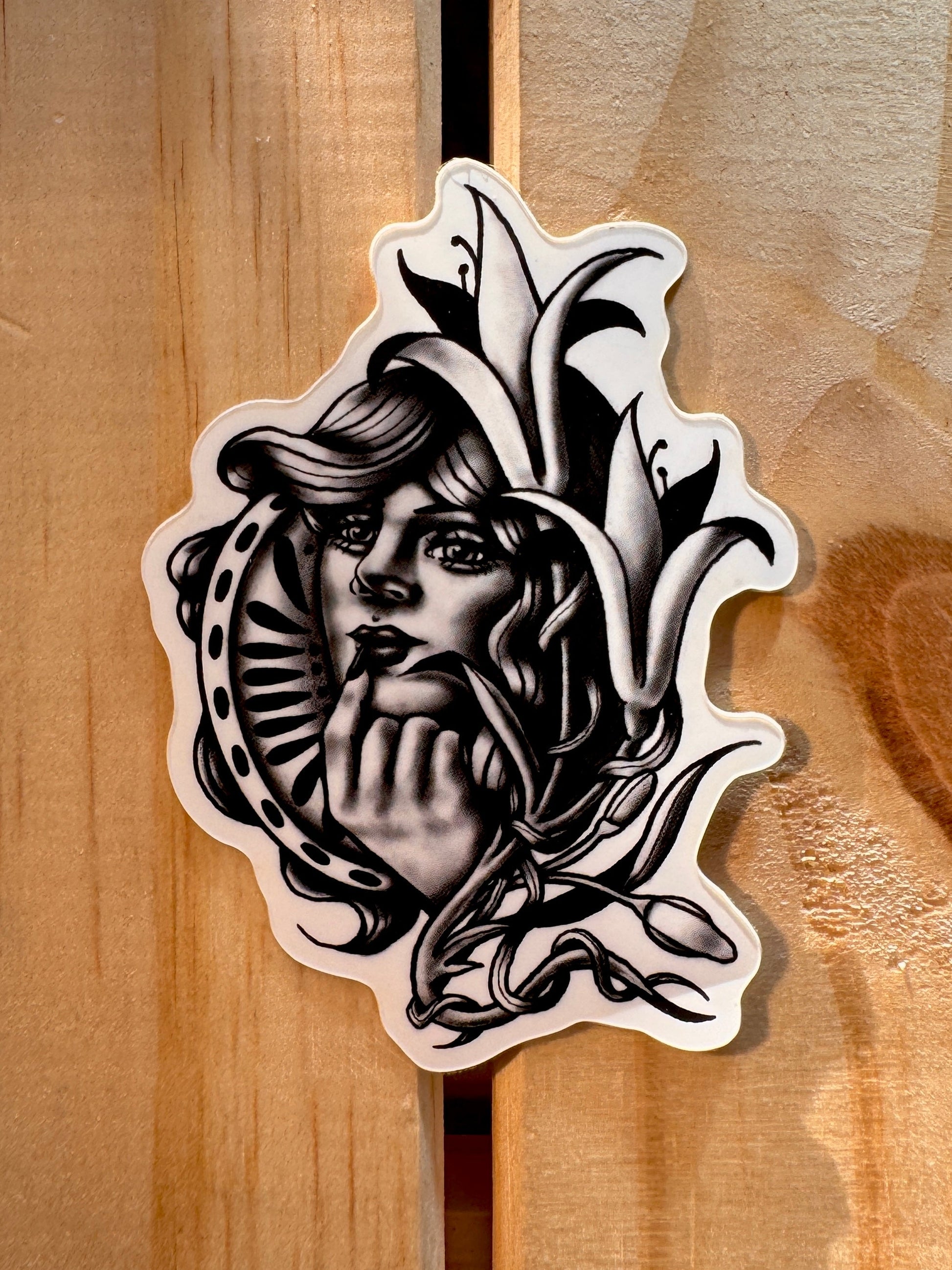 Black and grey sticker of a neotrad woman surrounded by lillies 